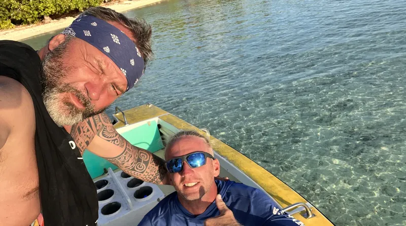 Deux hommes souriants sur un bateau jaune en mer