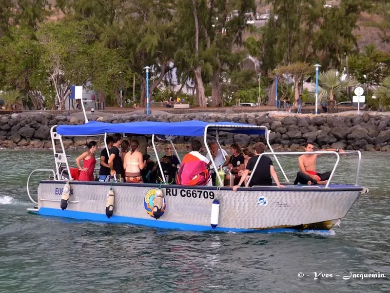 Plongeurs à bord d'un bateau gris naviguant sur une mer calme