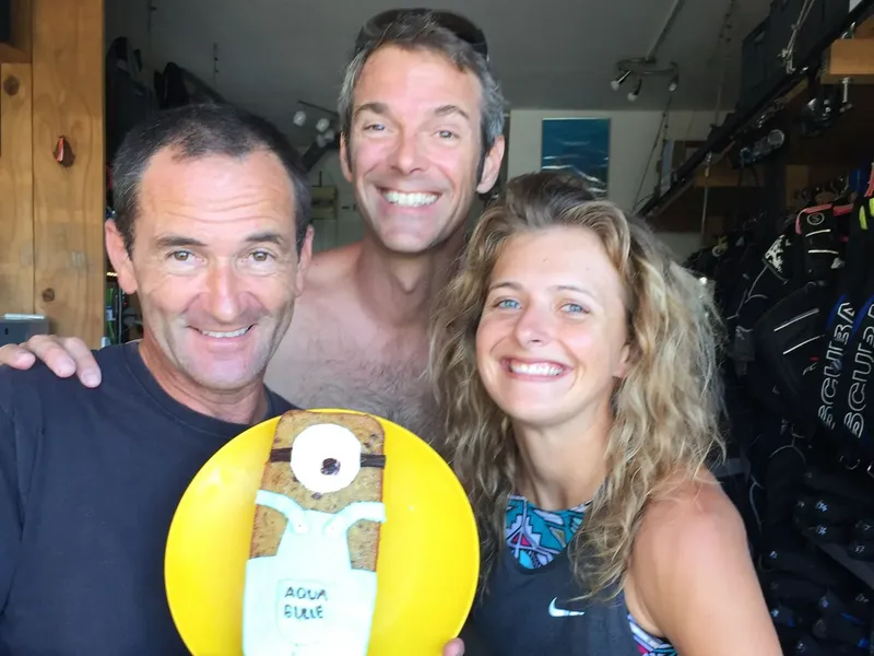 Trois personnes souriantes posent avec un objet jaune et du matériel