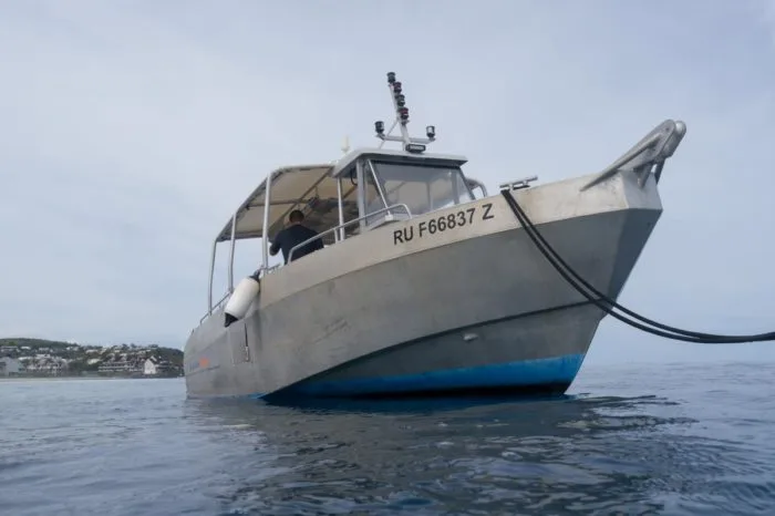 Bateau de plongée gris en mer avec une personne à bord