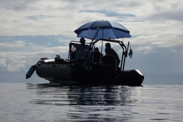 Bateau semi-rigide avec passagers et parasol sur l'eau calme