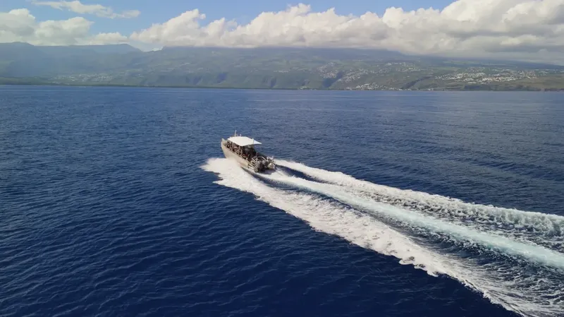 Bateau de plongée naviguant sur une mer bleue avec des montagnes