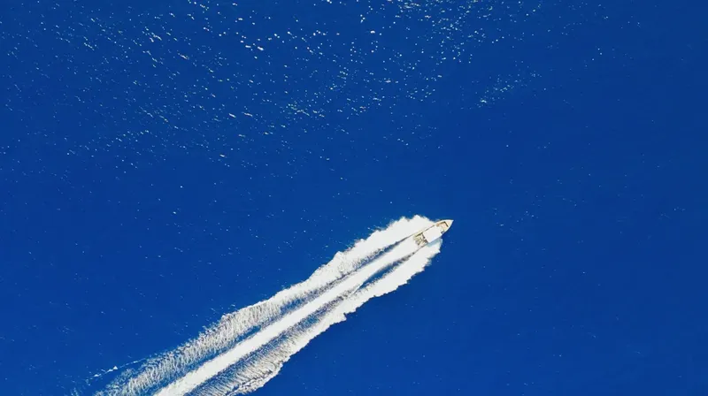 Bateau rapide naviguant sur une mer bleue avec une trace blanche