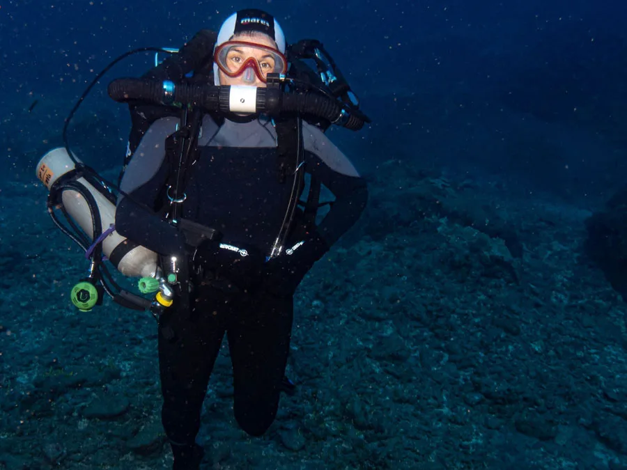 Plongeur en combinaison noire, masque et détendeur, explorant les fonds marins