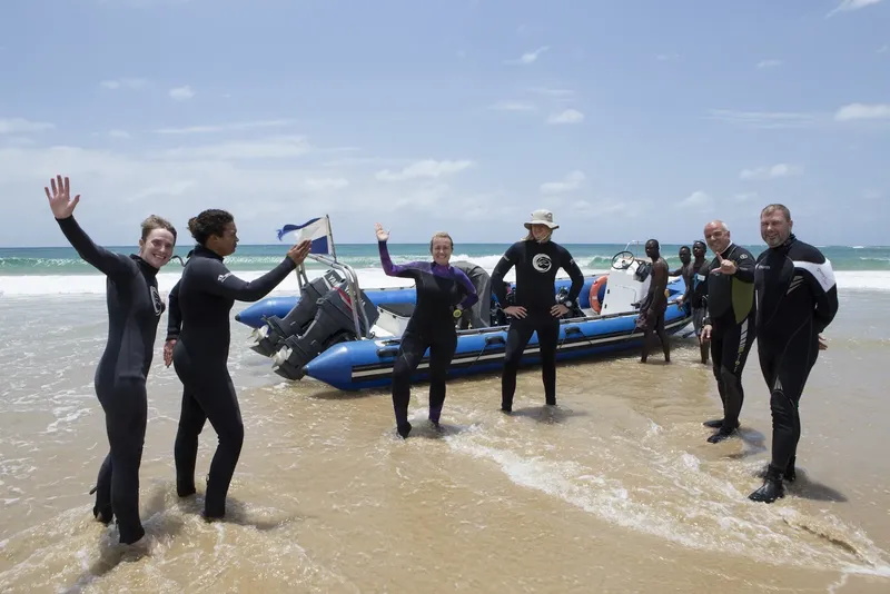Groupe de personnes en combinaisons de plongée sur une plage ensoleillée