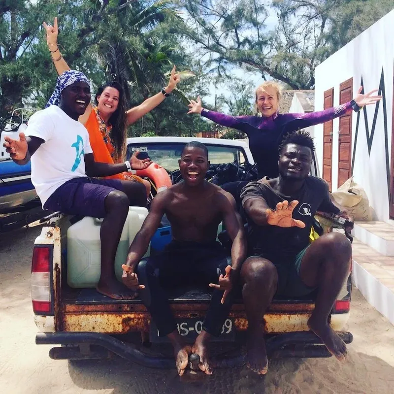 Quatre personnes souriantes posent sur le plateau d'un pick-up blanc