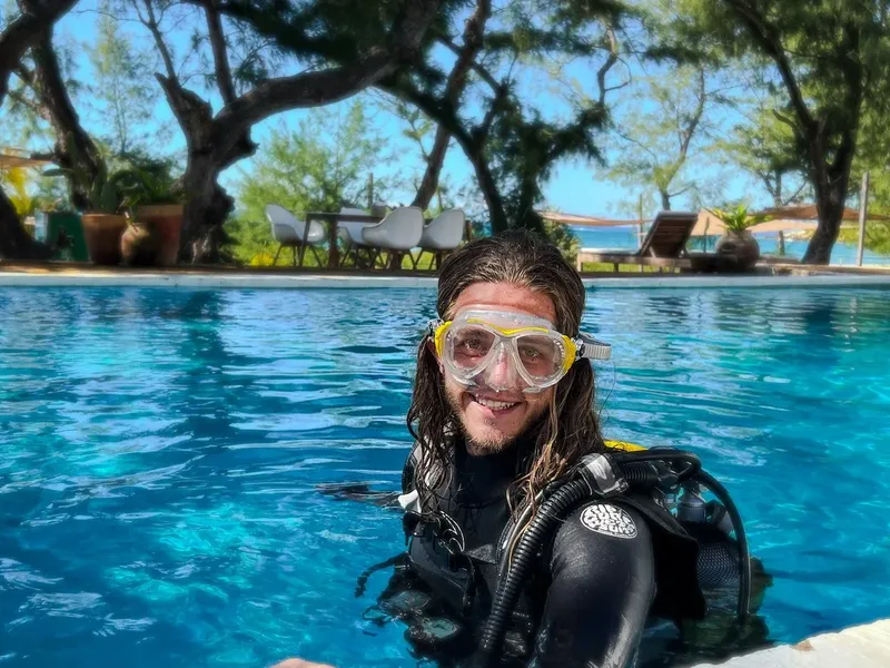 Plongeur souriant avec masque et équipement dans une piscine bleue