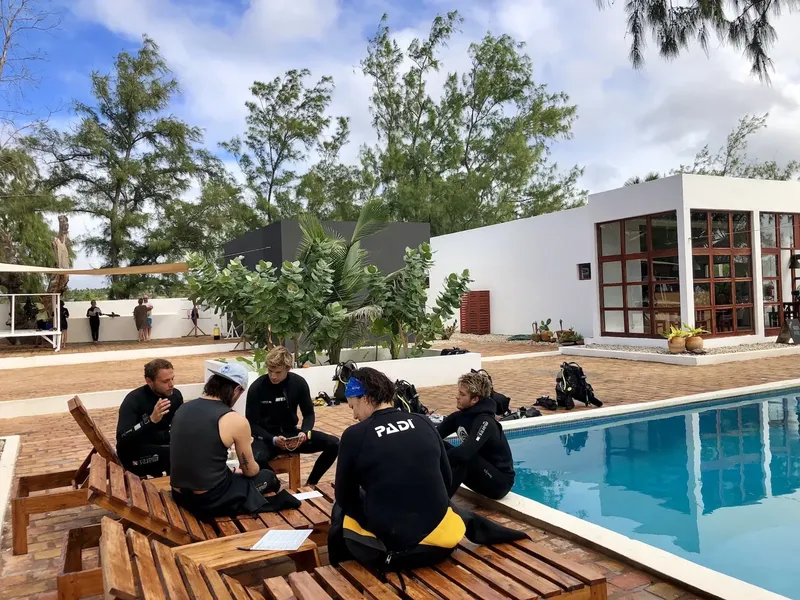 Groupe de plongeurs assis près d'une piscine avec équipement