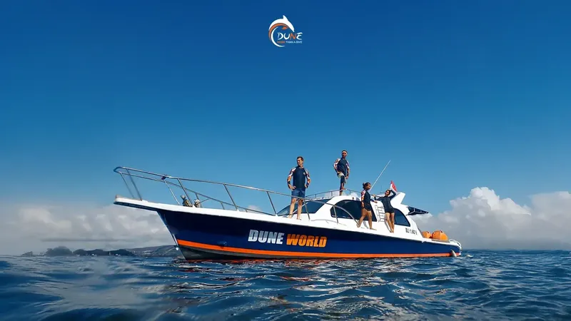Bateau de plongée bleu et orange avec des personnes à bord en mer