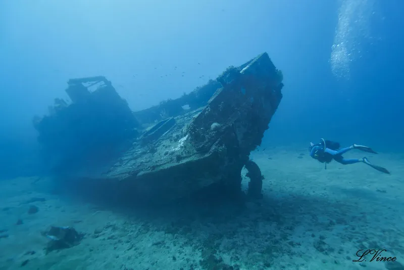 Plongeuse explorant l'épave d'un navire sous l'eau, lumière bleue