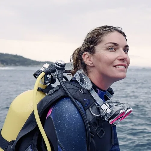 Plongeuse souriante avec son équipement complet regardant vers l'horizon