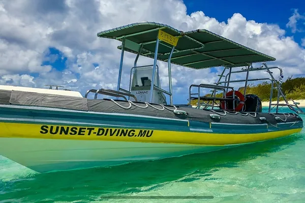 Bateau de plongée semi-rigide jaune et noir sur eau turquoise claire