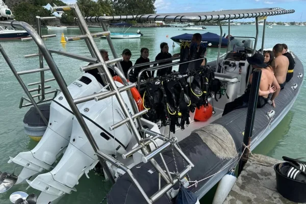 Plongeurs équipés sur un bateau semi-rigide près d'un quai ensoleillé