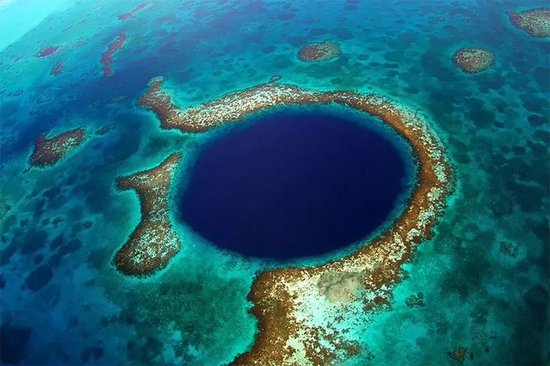 Vue aérienne d'un trou bleu entouré de récifs coralliens turquoise