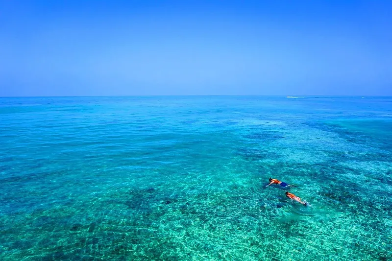 Deux personnes flottent en surface dans une eau turquoise claire