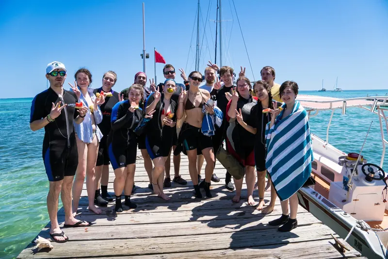 Groupe de personnes souriantes sur un ponton en bord de mer
