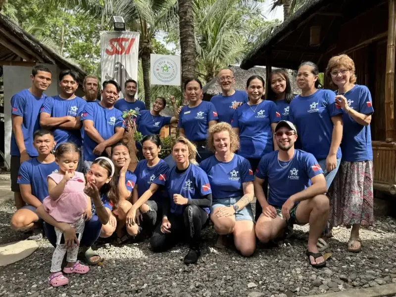 Groupe de personnes souriantes posant devant une structure en bois