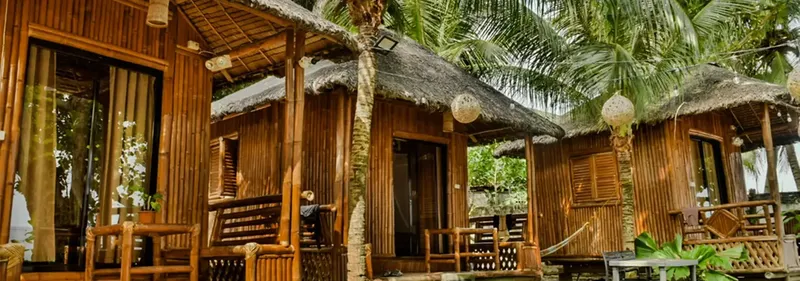 Cabanes en bambou avec toits de chaume, végétation tropicale luxuriante