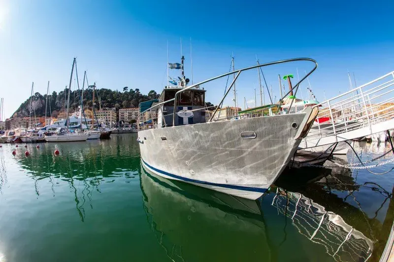 Bateau de plongée amarré dans un port ensoleillé avec des montagnes