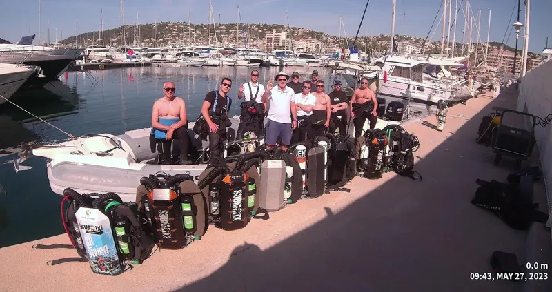 Groupe de plongeurs souriants posent avec un bateau et du matériel
