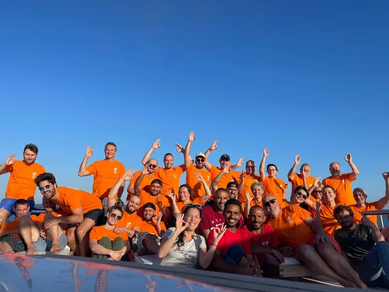 Groupe de personnes souriantes sur un bateau en mer, ciel bleu
