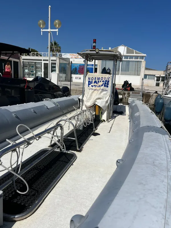 Bateau de plongée amarré devant un bâtiment blanc avec du matériel