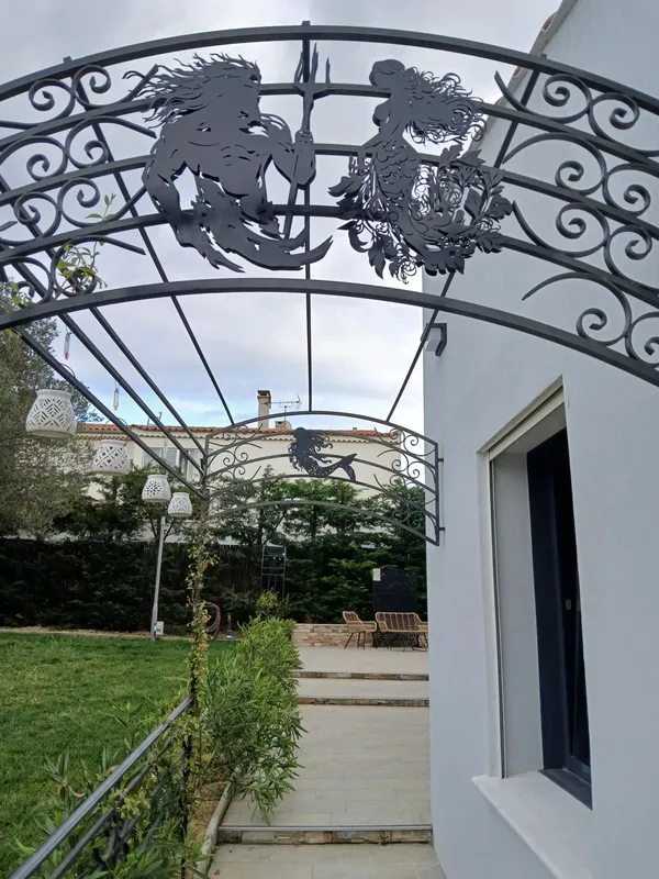Arc en fer forgé décoré de créatures marines devant un bâtiment