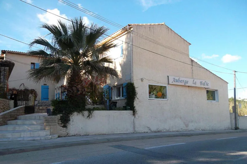 Façade d'un bâtiment beige avec un palmier et une entrée bleue