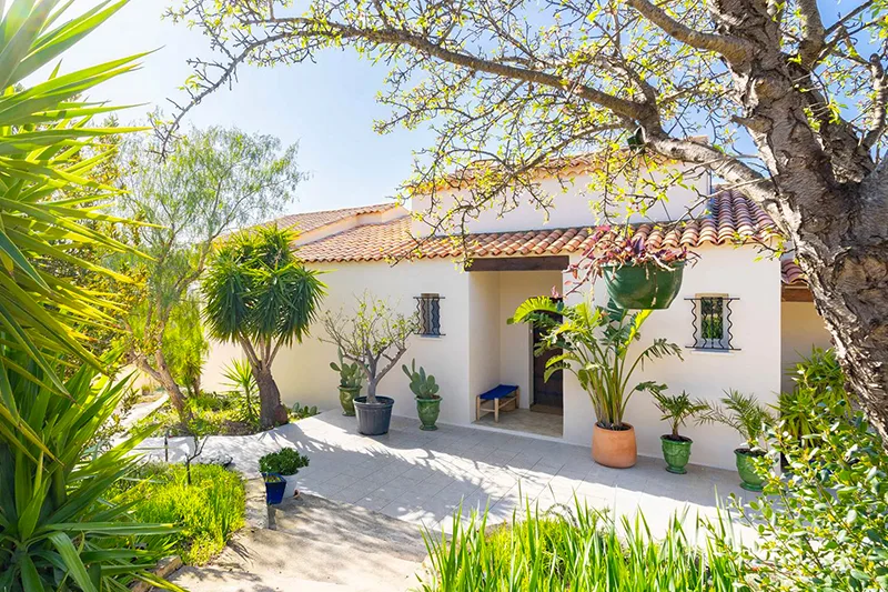 Façade d'un bâtiment blanc avec jardin fleuri et végétation luxuriante