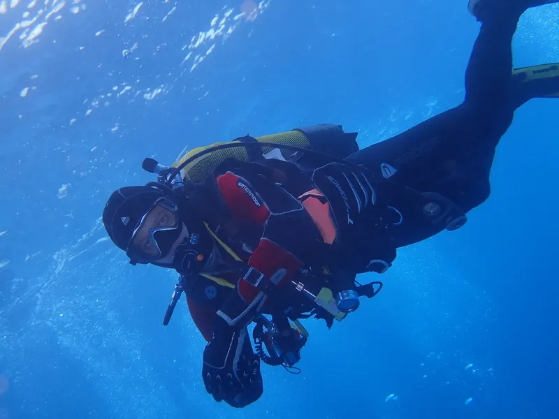 Plongeur en combinaison noire et jaune explorant les profondeurs marines