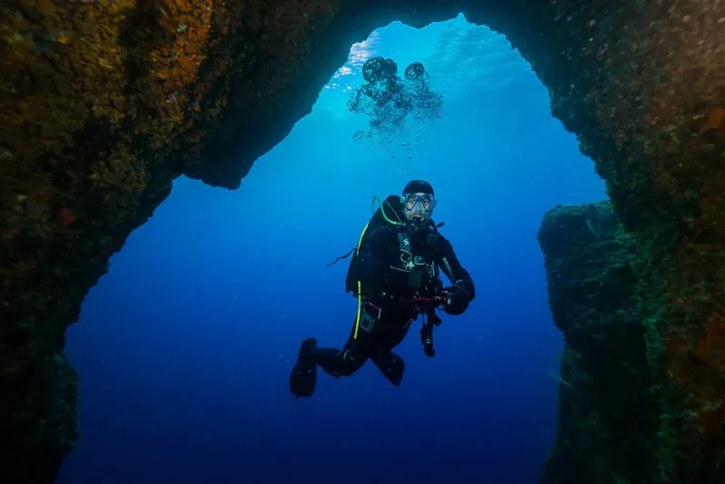 Plongeur explorant une grotte sous-marine avec une lumière bleutée