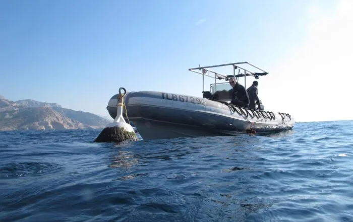 Bateau semi-rigide en mer avec deux personnes à bord et bouée