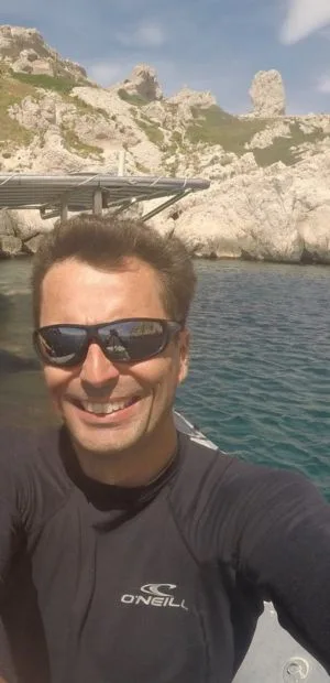 Homme souriant portant des lunettes de soleil sur un bateau en mer