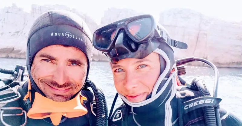 Deux plongeurs souriants en équipement complet, prêts pour une immersion