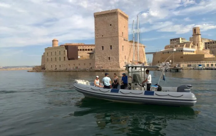 Un semi-rigide transporte des personnes devant un fort historique en pierre