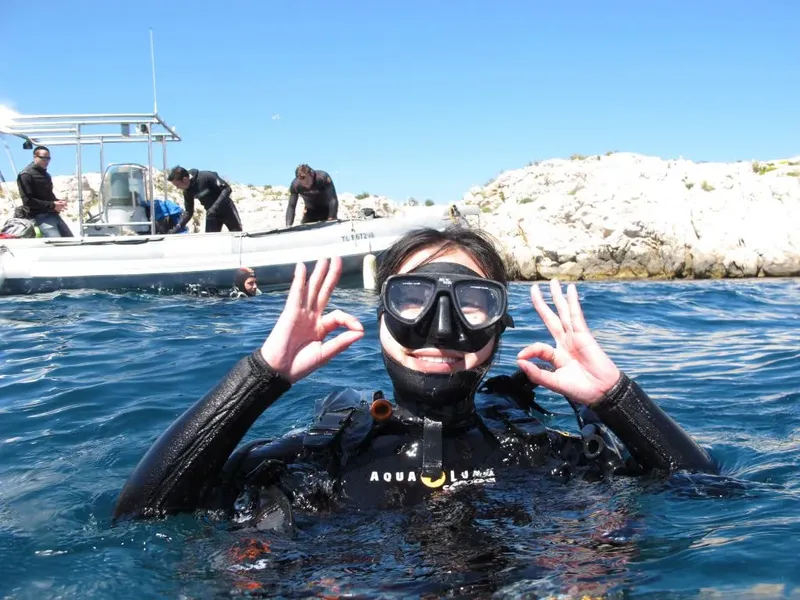 Plongeuse souriante avec masque et combinaison, geste OK, en mer