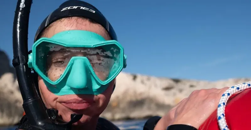 Plongeur avec masque turquoise et tuba, souriant, regardant la caméra