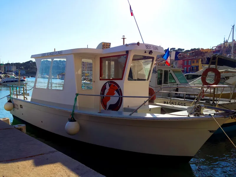 Bateau de plongée amarré dans un port ensoleillé avec des bâtiments colorés