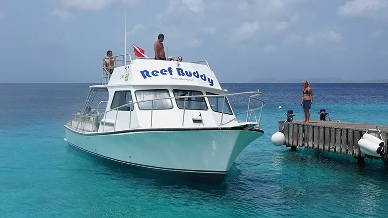 Bateau de plongée amarré à un ponton avec des personnes à bord