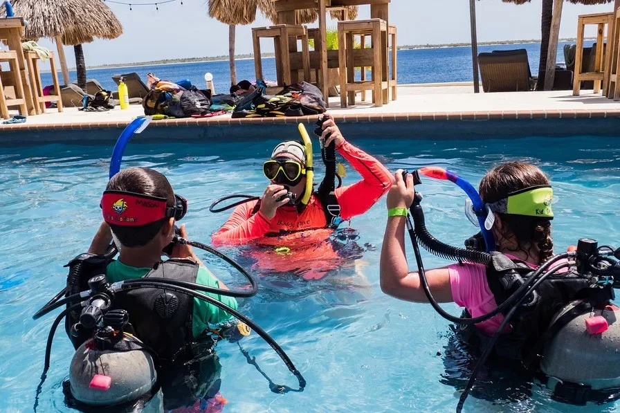 Trois personnes en équipement de plongée s'entraînent dans une piscine