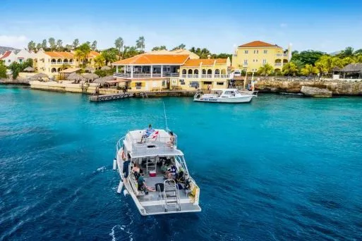 Bateau de plongée avec des passagers naviguant sur une eau turquoise claire