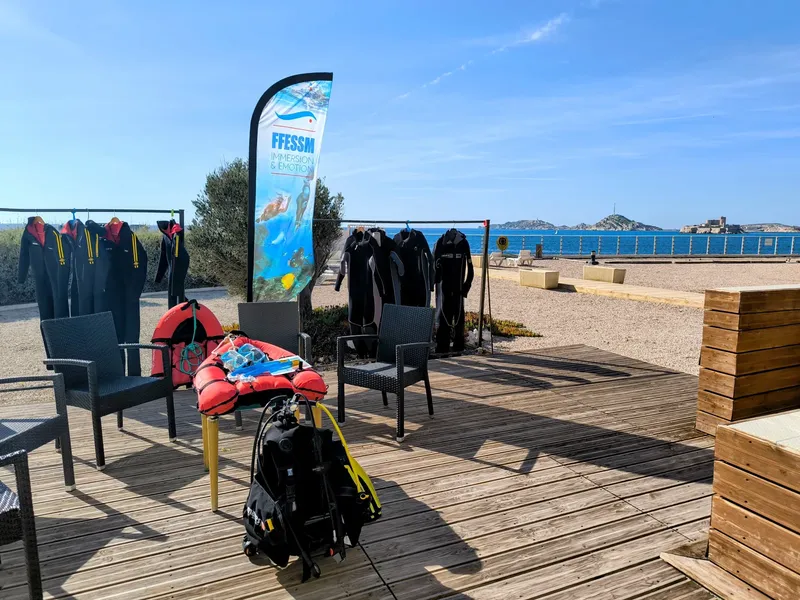 Terrasse en bois avec combinaisons, gilets et un panneau FFESSM bleu