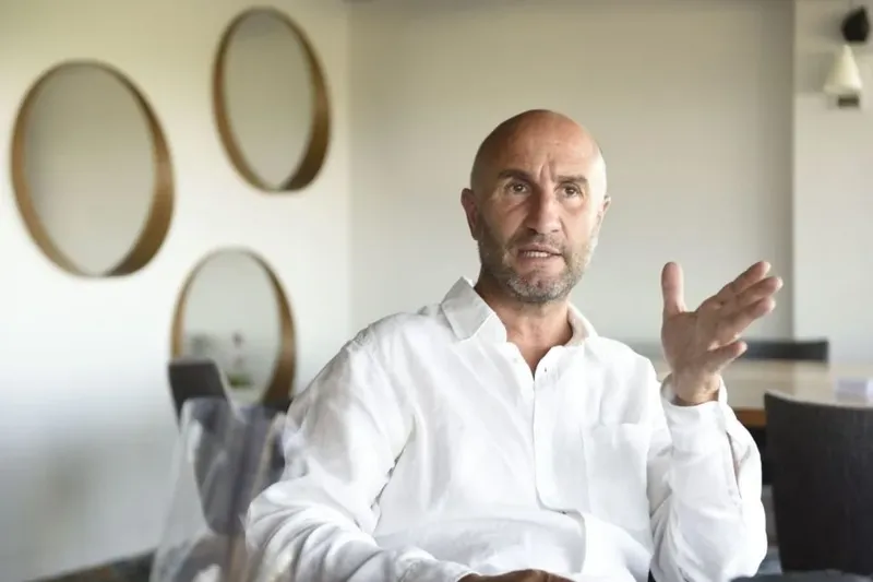 Homme chauve en chemise blanche gesticulant dans un intérieur clair