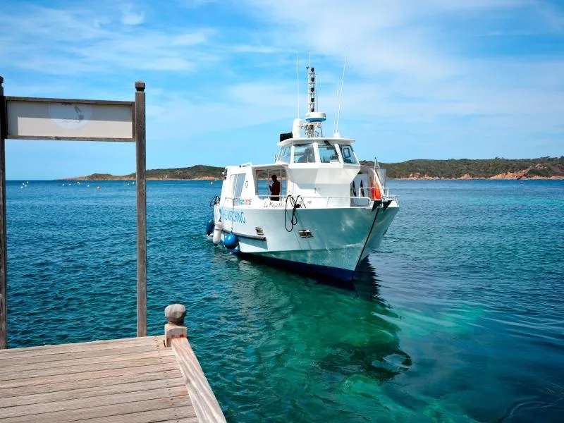 Bateau de plongée amarré à un ponton dans une eau turquoise claire
