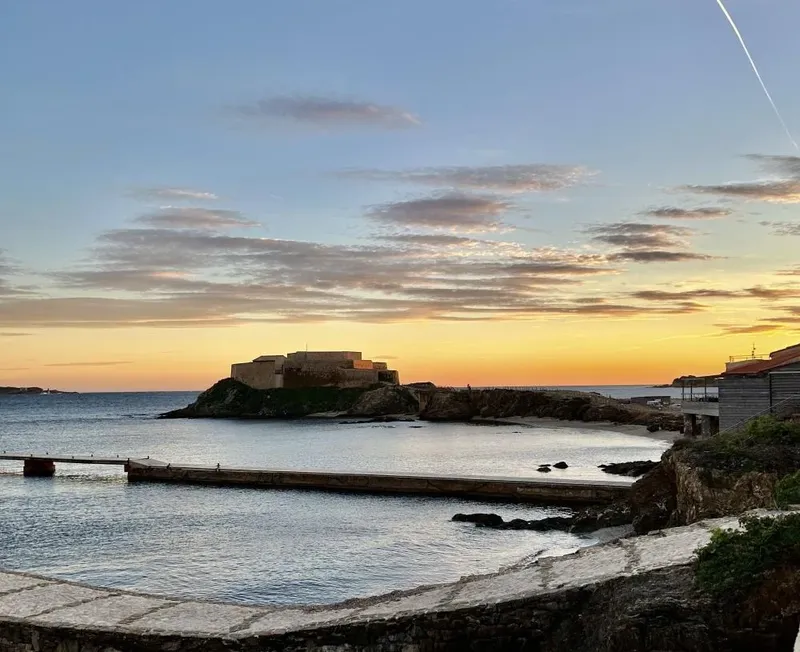 Coucher de soleil sur une forteresse maritime et un quai rocheux
