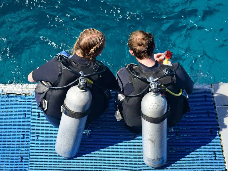 Deux plongeurs assis sur un ponton vérifient leur équipement
