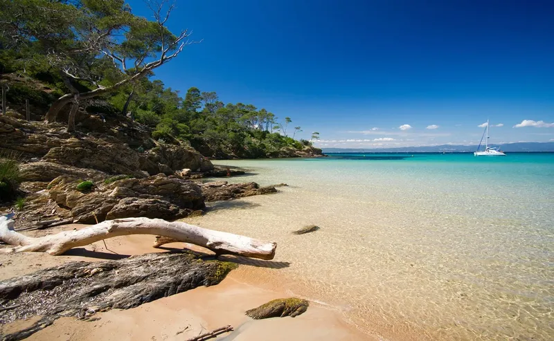 Plage de sable fin avec un bateau à voile en mer turquoise