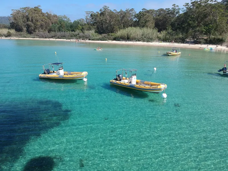 Plage ensoleillée avec des bateaux pneumatiques et des personnes dans l'eau