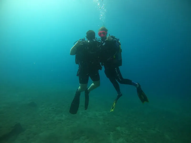 Deux plongeurs en combinaison explorent les fonds marins bleus et clairs