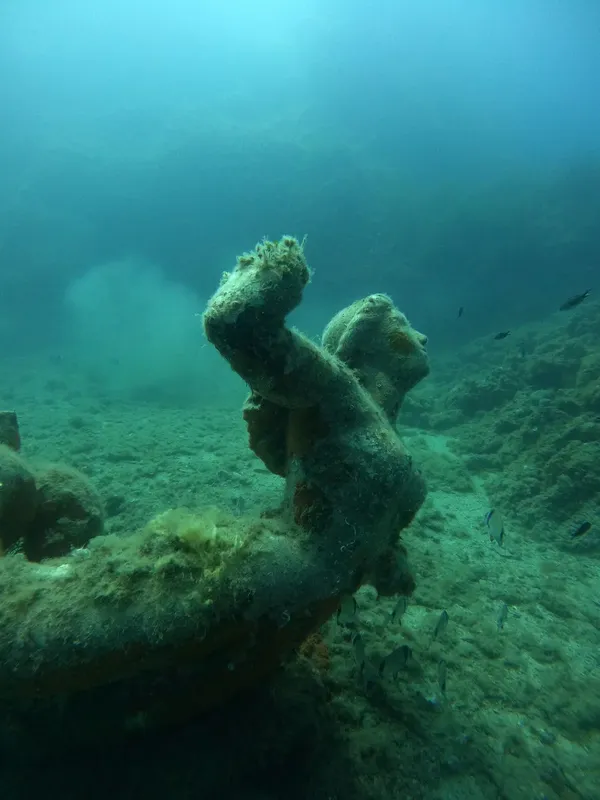 Sculpture sous-marine recouverte d'algues et habitée par des poissons